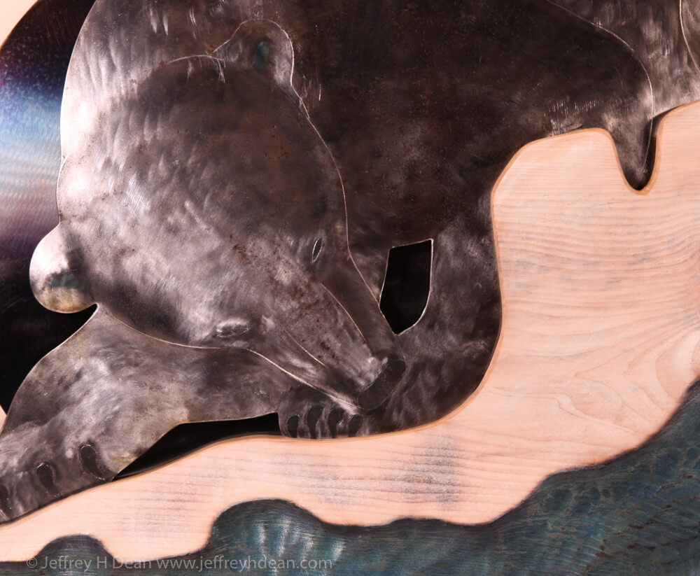 A lone polar bear and an arctic fox watch stealthily as a seal rises under it's breathing hole in this layered steel and wood relief.