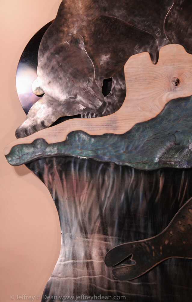 A lone polar bear and an arctic fox watch stealthily as a seal rises under it's breathing hole in this layered steel and wood relief.