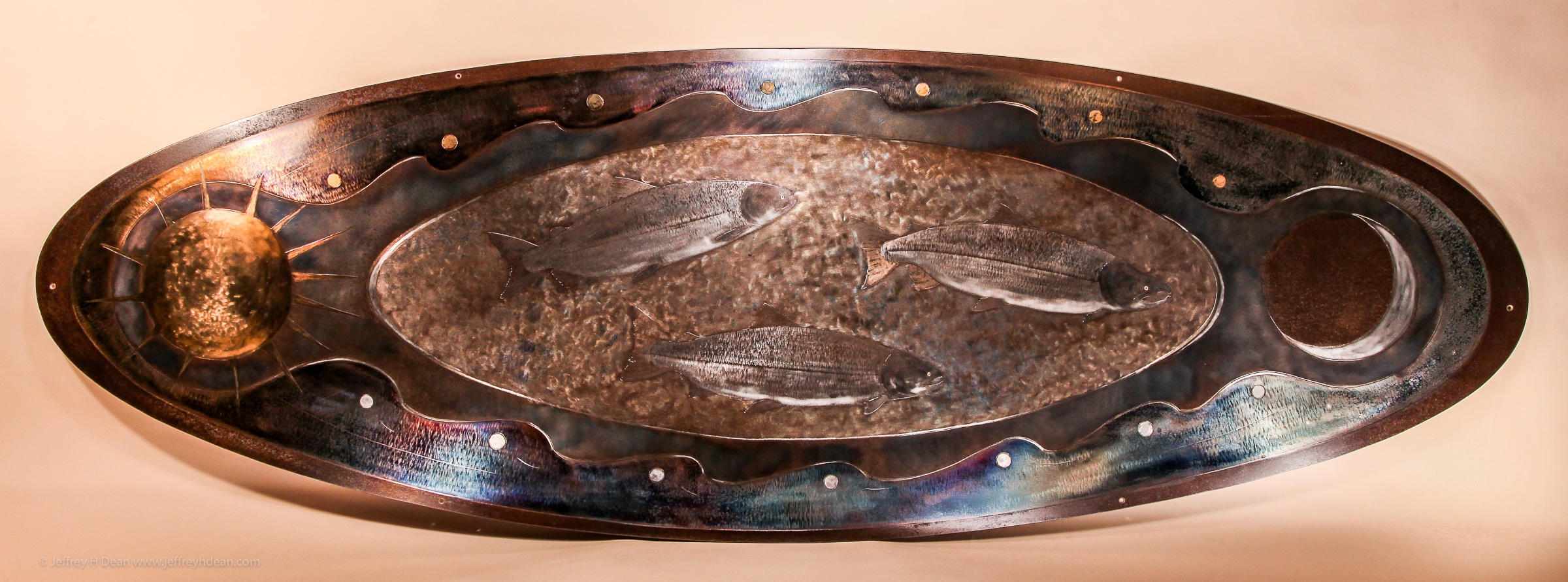 Salmon metal wall art. Three silver salmon swim between the tides, the sun and moon in this engraved and heat tinted steel metal wall art.