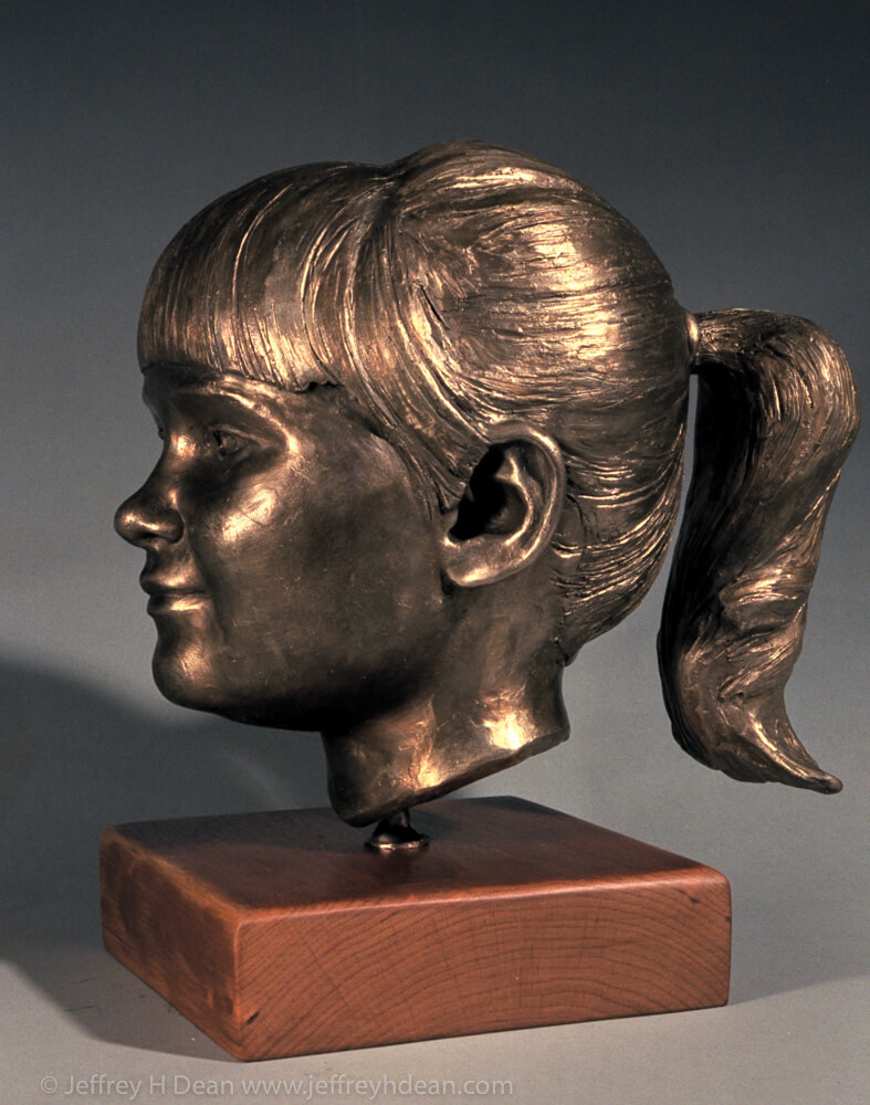 Bronze portrait of a young girl with pony tail.