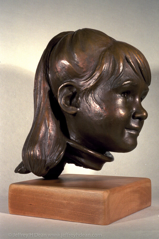A bronze portrait sculpture of a young girl.