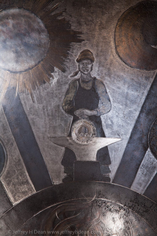 Earth, air, fire and water; the resources of the smith. Engraved steel sawblade of blacksmith in the forge.
