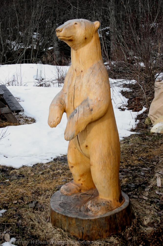 White spruce carving of polar bear in the rays of the first arctic sun.
