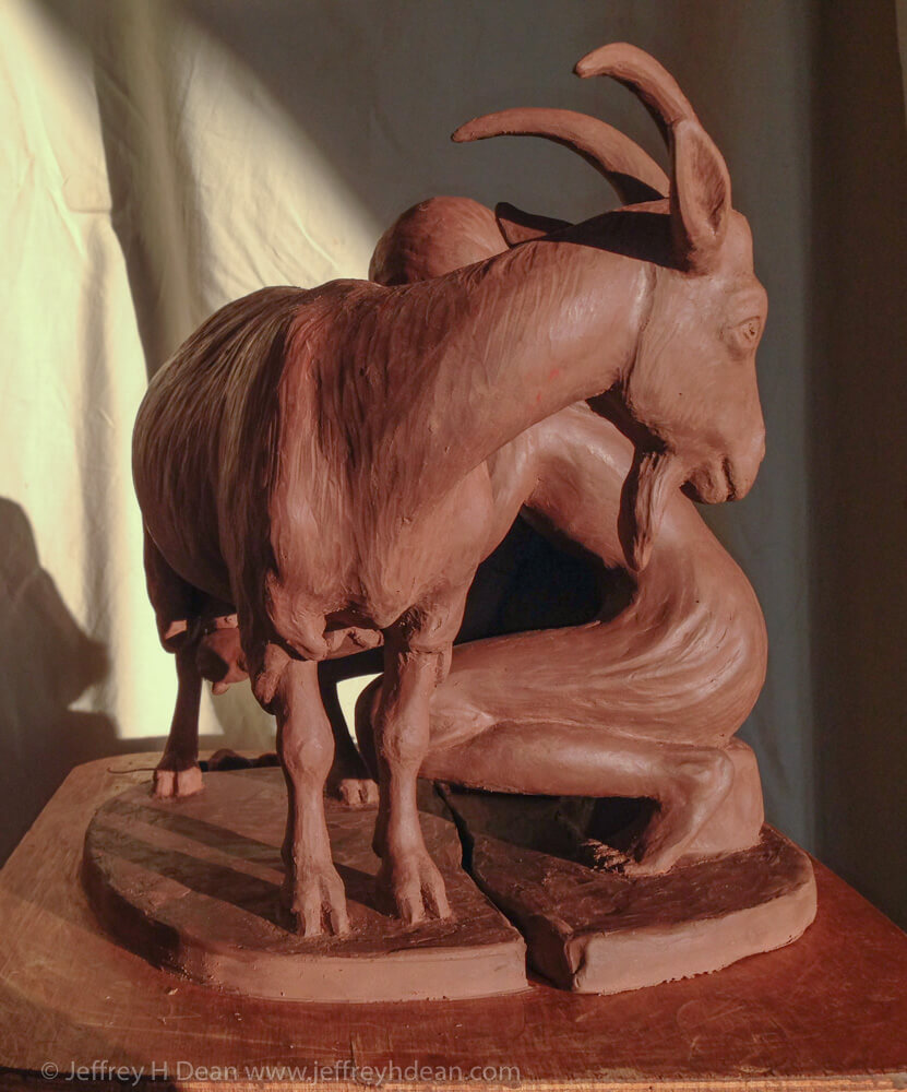 Clay model for bronze sculpture of girl milking goat.