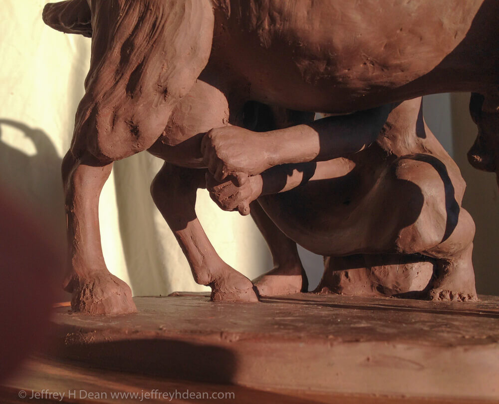 Clay model for bronze sculpture of girl milking goat.