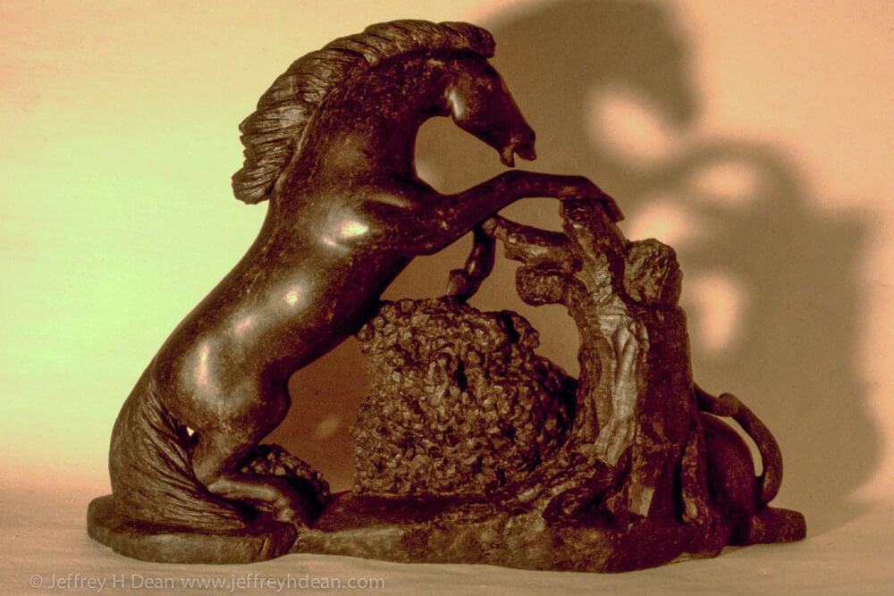 Soapstone carving of rearing horse and mountain lion.