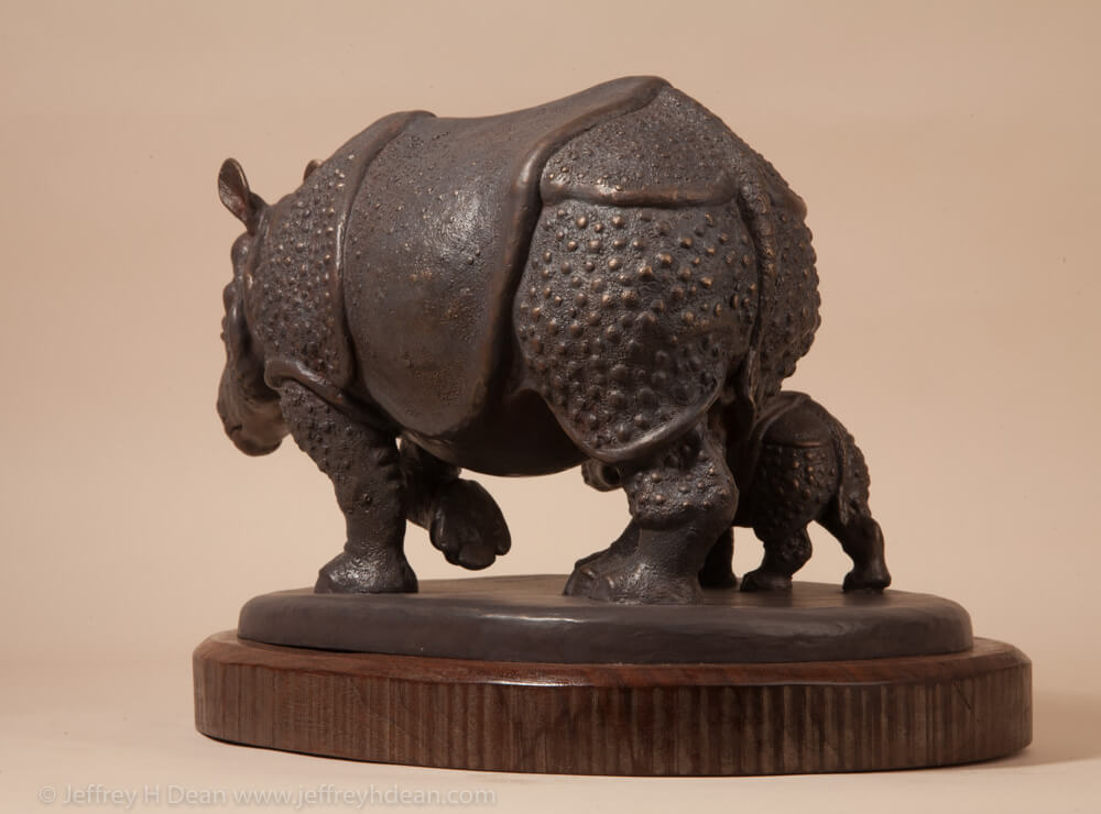 Bronze sculpture of a mother Indian rhino walking with her baby.