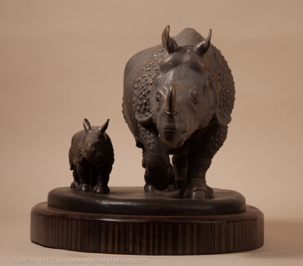 Bronze sculpture of a mother Indian rhino walking with her baby.