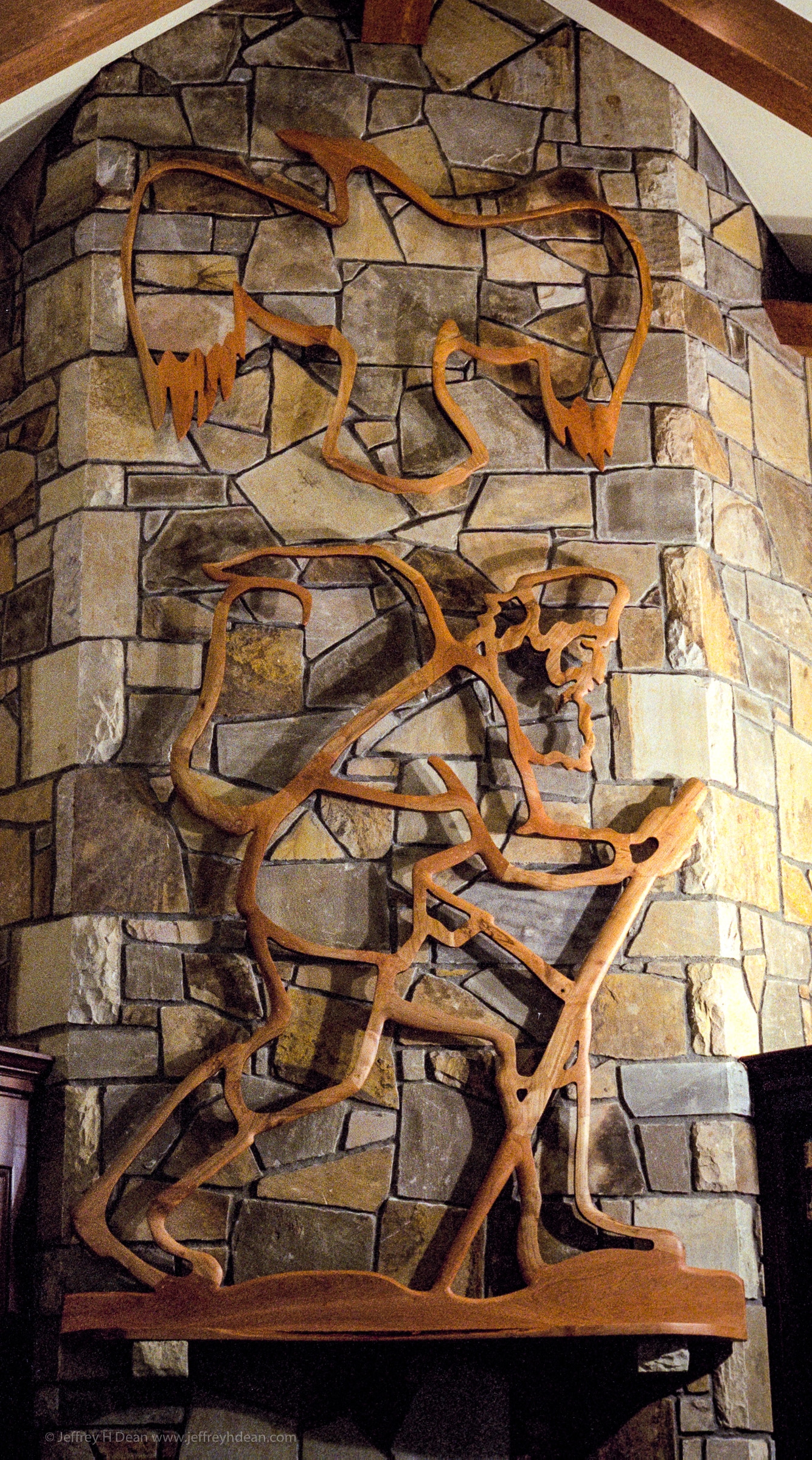 Fireplace mantle and pierced cherry relief of hiking mountain man and raven.