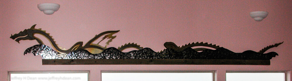 Wall relief of sea dragon frolicking in the waves. Weathered fir, stainless steel and brass.