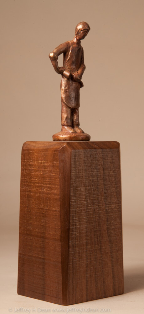 Bronze miniature sculpture of a woodcarver holdiing his mallet and chisel.
